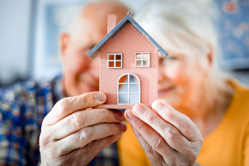 Bild Senioren die ein Miniaturhaus halten Symbol für Seniorenumzug